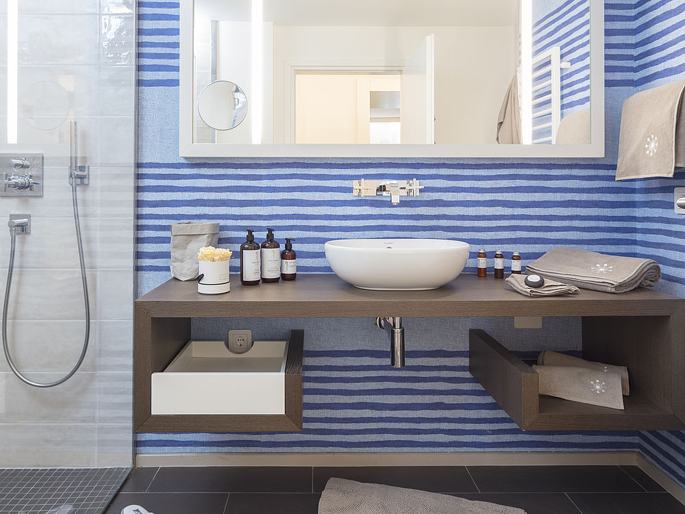 Badezimmer mit großer Duschkabine, braunen Holzmöbeln und blau gestreifter Rubelli Wandfarbe im Marine-Style