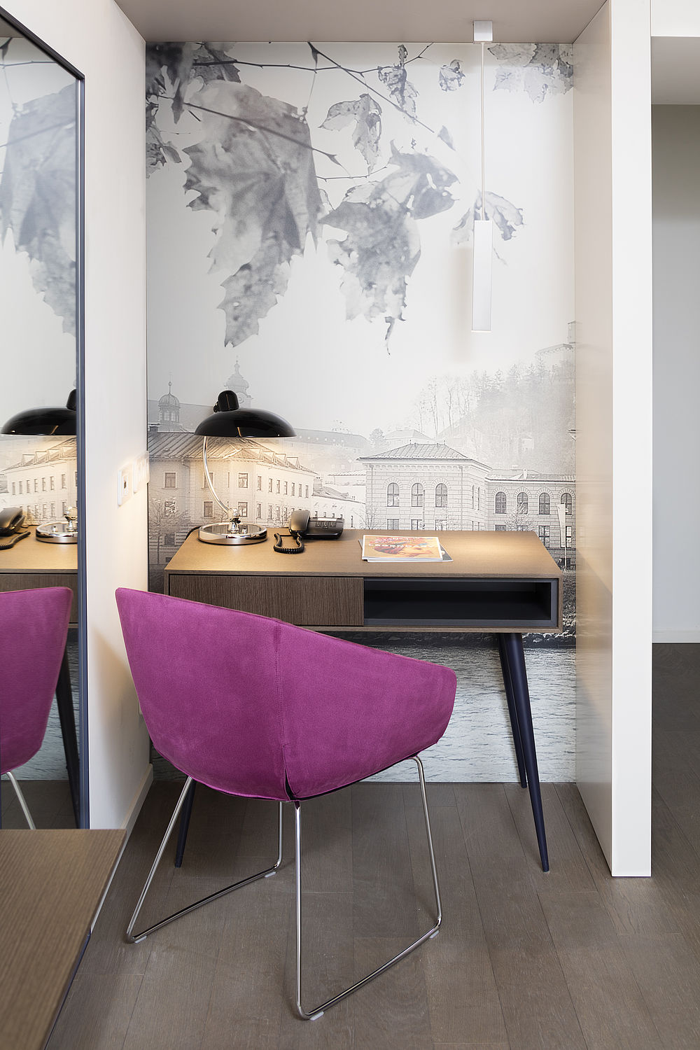 Working Space eines Zimmers im Luxushotel in Salzburg mit magentafarbenem Samtsessel, kleinem Holztisch und Schreibtischlampe