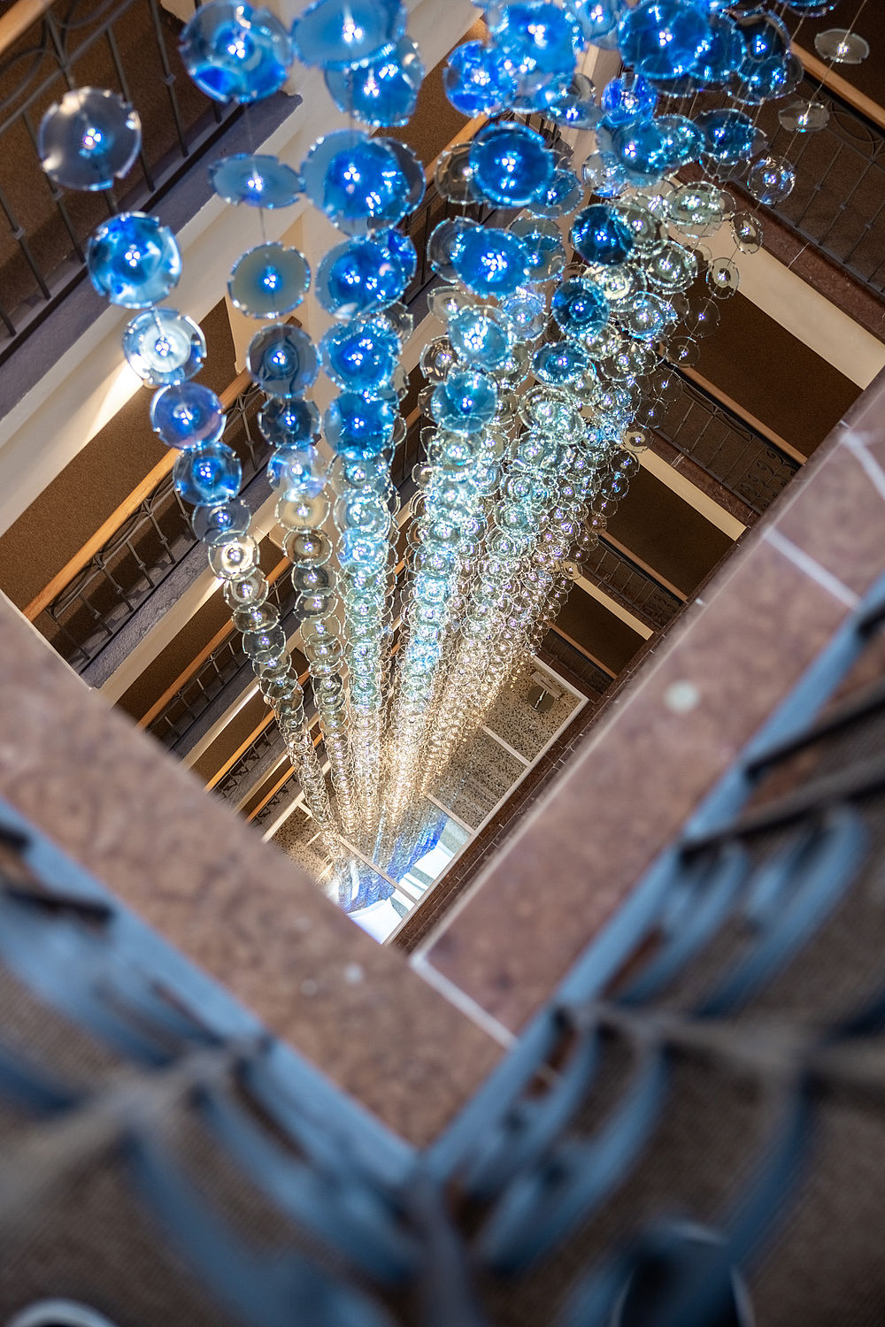 Designerlampe aus hunderten Lämpchen in blau-weißen Glasscheiben die im Treppenhaus des Hotel Stein als leuchtende Kaskade hängen