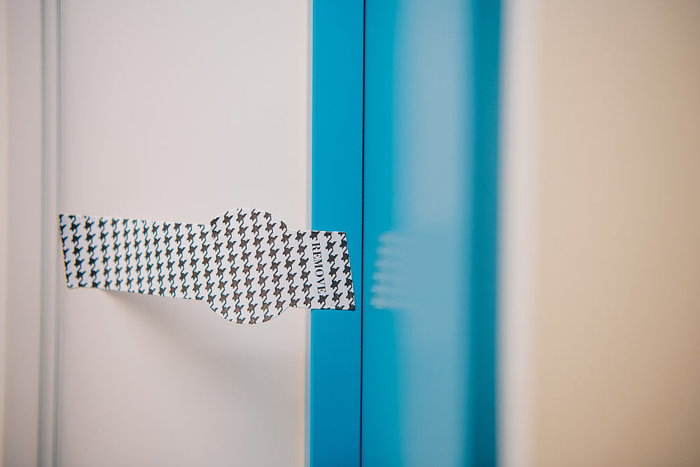 Ein Aufkleber mit der Aufschrift "Remove" ist an einem hellblauen Türrahmen befestigt