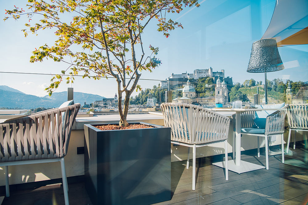 Terrasse des Restaurants mit weißen Stühlen und Tischen und Blick auf Altstadt und Festung
