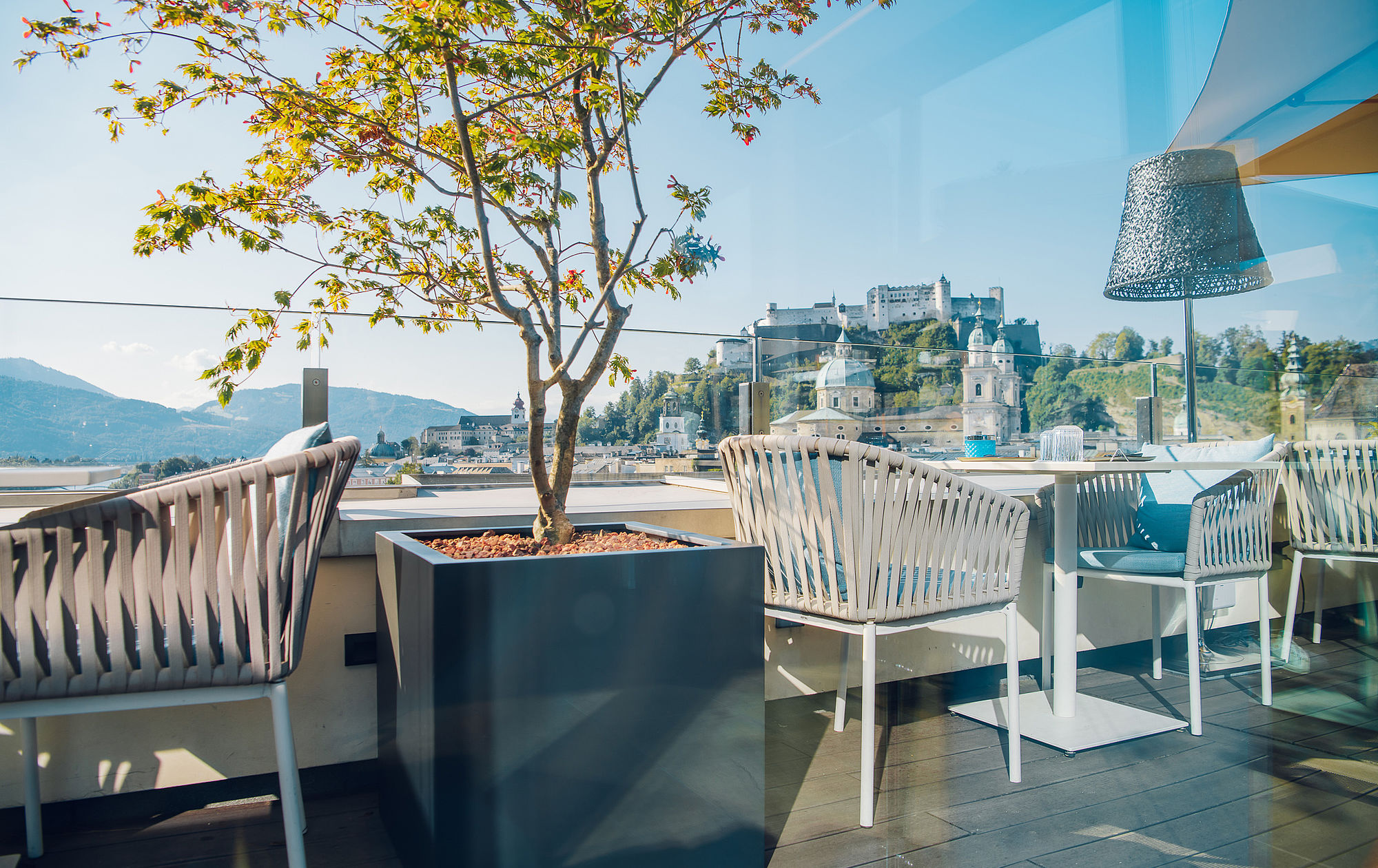 Terrasse des Restaurants mit weißen Stühlen und Tischen und Blick auf Altstadt und Festung