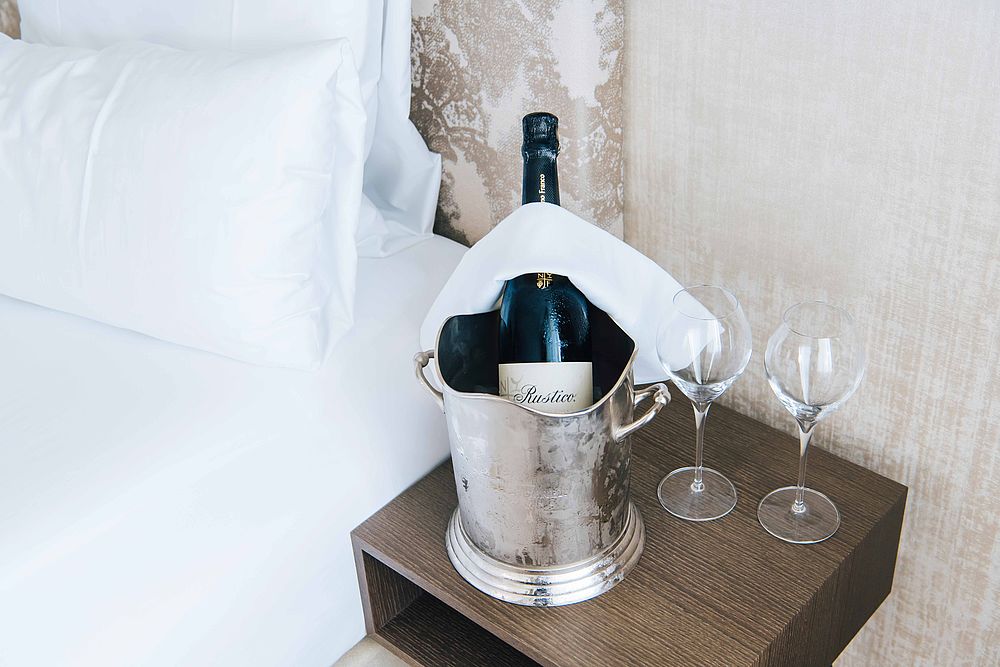 Eine Weinflasche Rustico in einer Edelstahl-Schale mit 2 Weingläsern auf dem Nachttisch des Hotelzimmer im Luxushotel Stein
