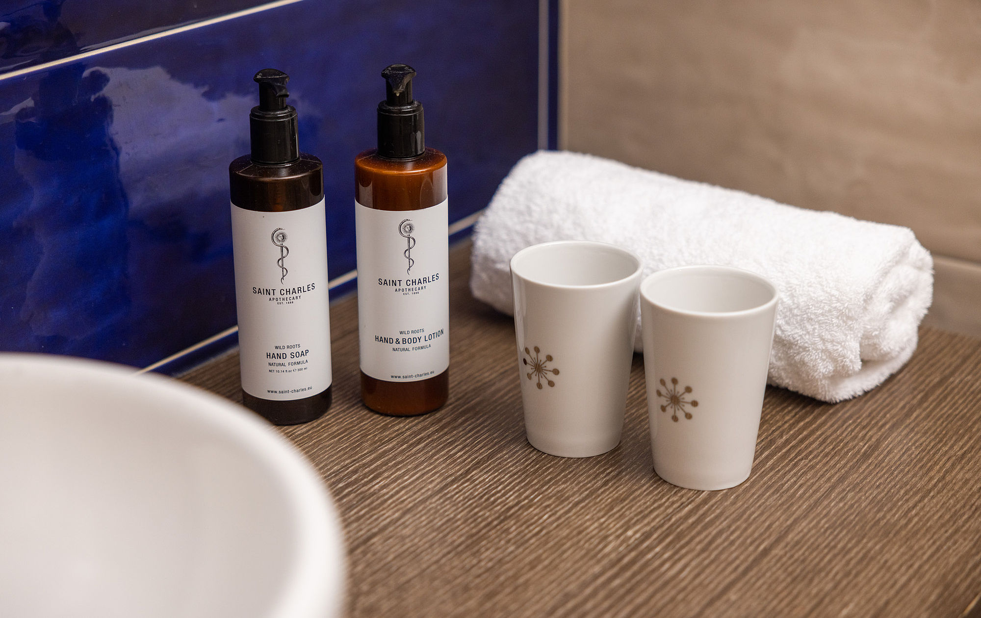Natural cosmetics, white mugs and a freshly rolled up towel in the bathroom of Hotel Stein in Salzburg