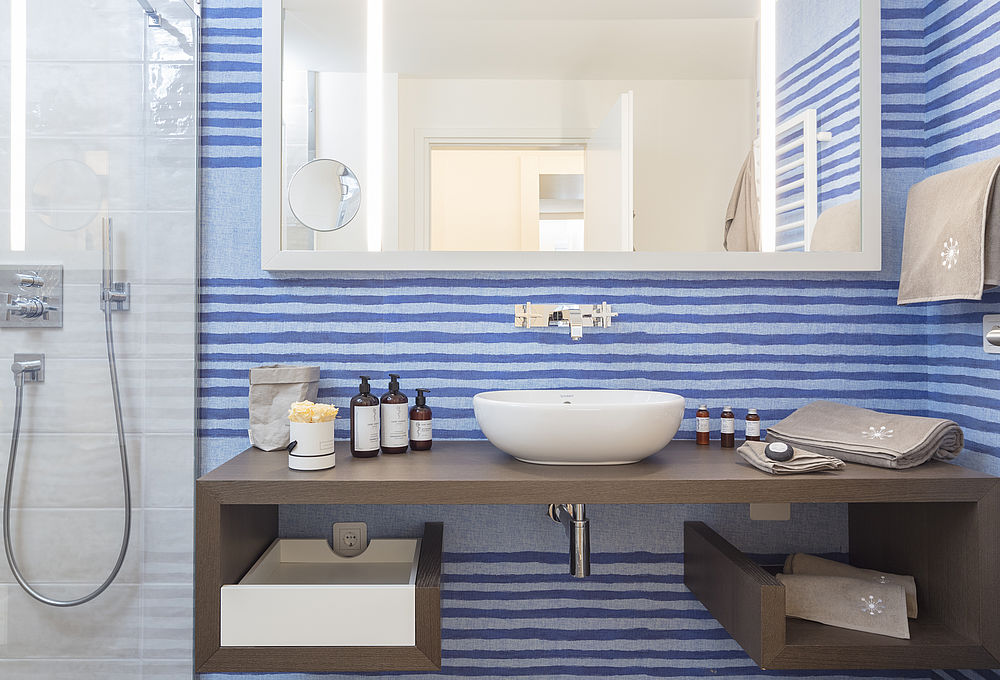 Modernes Badezimmer des Luxushotels in Salzburg, im Marine-Design mit Rubelli Tapeten und heller Duschkabine und großem Waschtisch aus Holz